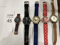 Top-down view of five wrist watches laid flat in a row.