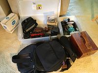 Overview of cameras, carrying bags, and boxed items in plastic bin
