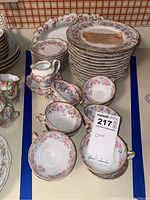 Full view of china set showing teacups, plates, cream pitcher, and serving pieces arranged on table.