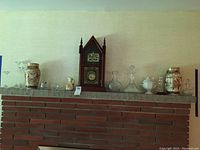 Wide view of mantel displaying clock, vases, decanters, small glass bowls and glasses