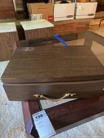 Closed dark brown wood box with gold-tone handle for flatware storage