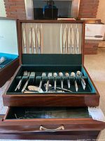 Photo of wood storage box holding the full flatware set, with knives in upper compartment and forks, spoons, and completer pieces in lower compartment.