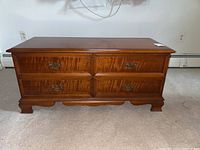 Full front view of wooden cedar chest showing two drawers with brass handles and bracket feet.