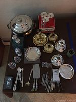Full view of the collection showing the covered casserole, salt and pepper shakers, candlesticks, serving utensils, and trays arranged on a table.