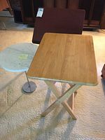 Overall view of the three tables showing wooden TV tray, marble top side table, and wooden writing table indoors on carpet.