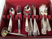 Set of 32 pieces of polished stainless steel flatware inside red lined wood storage case, showing forks, spoons, knives, ladle, and serving utensils.