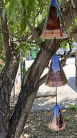 Full view of the ceramic windchimes hanging on a tree, showing their shape, colors and outdoor setting.