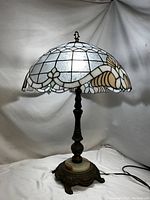Full view of the Tiffany style lamp showcasing the stained glass shade with floral patterns, brass stem, and marble base.