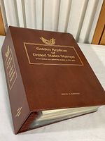Collector's album cover for Golden Replicas of United States Stamps, brown color with gold text and an eagle emblem, spine also labeled.