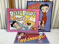 Three reproduction Betty Boop metal signs assembled with colorful vintage-style artwork and text, largest sign around 16 x 12 inches.