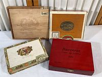 Four vintage cigar boxes arranged showing top designs and logos.