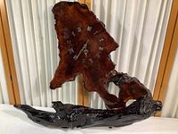 Front view showing the large freeform wood sculpture with clock face and Roman numerals.