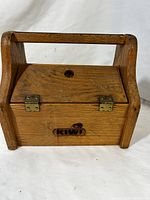 Front view of the wooden shoeshine box with Kiwi logo on front panel.