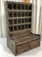 Front view showing multiple small cubbies arranged diagonally above a wide drawer with knob.