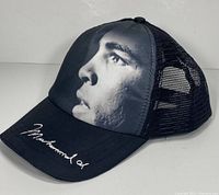 Front and side angle showing black and white profile face of Muhammad Ali and embroidered signature on the brim.