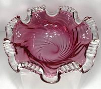 Top-down view showing the crimped edges, ridged clear glass rim sections, and deep cranberry swirl towards the center of the bowl