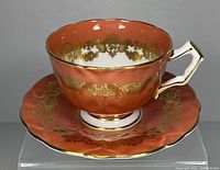 Photo of vintage Aynsley burnt orange and gold scroll porcelain teacup with matching saucer.