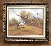 Framed vintage oil painting showing landscape scene with hunting dog and bird in flight, detail of entire artwork and frame.