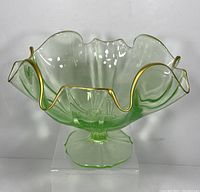 Front view of the vintage green glass pedestal bowl showing ruffled edge with gold trim and clear green glass.