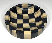 Front angled view showing the round shape, checkered black and beige marble pattern, and four cigar rests.