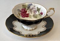 Photo of the tea cup and saucer showing floral interior and black and gold exterior design