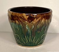 Front view of the planter showcasing the brown and green glazed sun and moon design