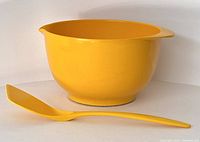 Yellow Rosti mixing bowl with minor wear, shown with matching yellow utensil placed in front.