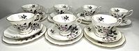 Six sets of Royal Albert Queen's Messenger teacup, saucer, and dessert plate arranged with one extra teacup and saucer