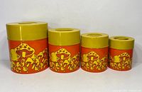 Four vintage tin nesting canisters lined up, showing mushroom pattern and yellow lids