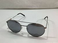 Pair of Joe Fresh sunglasses with silver metal frame and black oval lenses showing UV protection sticker.