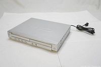 Front and side view of the silver Nova DV-D311 DVD player with power cord visible.