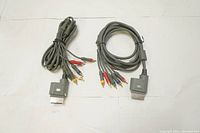 Two Microsoft Xbox adapter cables each with proprietary Xbox connector and RCA component audio/video plugs.