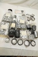 Overview of Sigma camera lens parts including labeled bags, rings, and cylindrical components spread on white surface.
