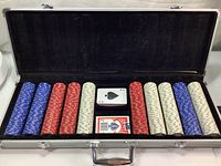 Open hard case showing rows of blue, red, and white weighted poker chips and two decks of playing cards inside