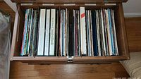 Wooden case with vinyl albums arranged inside showcasing a large variety of artists and genres including country and box sets.