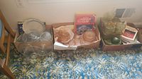 Overview of multiple glassware items including plates, bowls, cups, and boxes with books.
