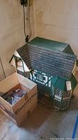 Photo showing assembled Tudor style doll house with green and white paint and adjacent box containing parts.