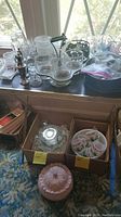 Overall view of the holiday glassware, mugs, bowls, candle holders on table by window.