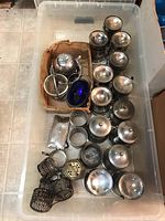 Overview of 13 silverplate canisters, sugar bowl in cardboard box, and 6 napkin rings in plastic bin.