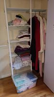 Shelf with folded sleepwear and plastic bin with more sleepwear below