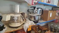 Photo showing Sears food processor with mixing container on left and Sunbeam stainless steel mixer on right on a metal garage shelf.