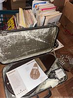 Suzuki Omnichord OM-27 in open brown hard case with sheet music and adapter visible