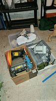 Overview of three containers: cardboard box of vehicles, gray plastic bin of panels, white bin of terrain pieces
