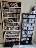 Two shelving units filled with music CDs in jewel cases arranged vertically and horizontally.