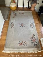 Floral patterned cream area rug with multiple floral designs and fringed ends, laid on hardwood floor