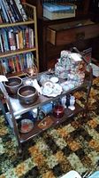 Full view of vintage metal cart with various household items on shelves, showing condition and structure.