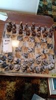 Top-down angled view showing full chess set arranged on 14x14 square marble board. Pieces in brown and beige marble.