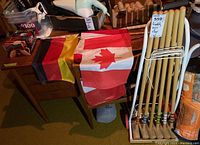 Croquet set with six wooden mallets and balls on a white stand next to three fabric flags (Canadian, German, French) laid on a surface.