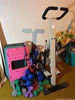 Wide view of low impact climber machine, aerobic steps, and dumbbells piled together.