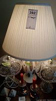 Close up of the lampshade with lot label and part of ceramic base visible.